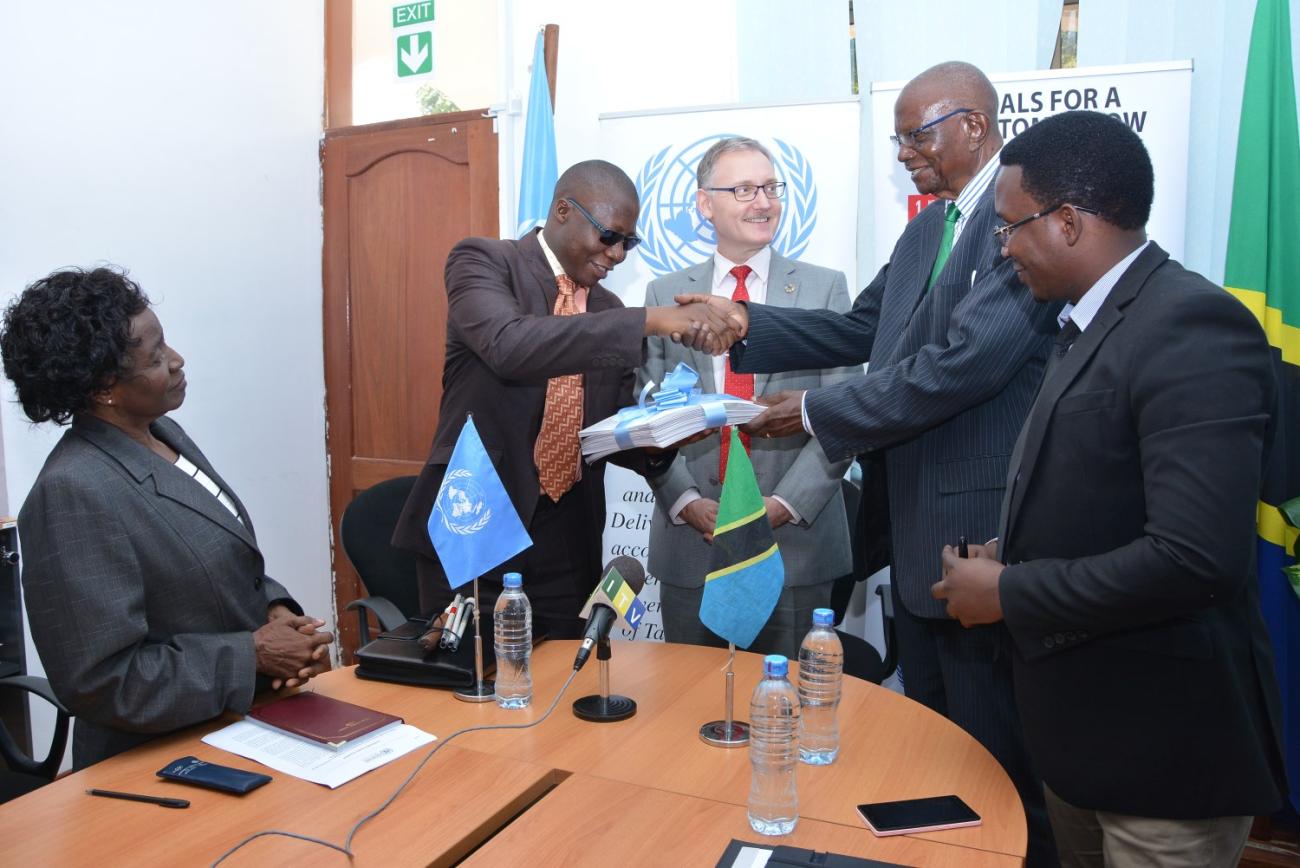 Mr. Amon Anastazi Mpanju (left) hands over Global Goals factsheets printed in braille
