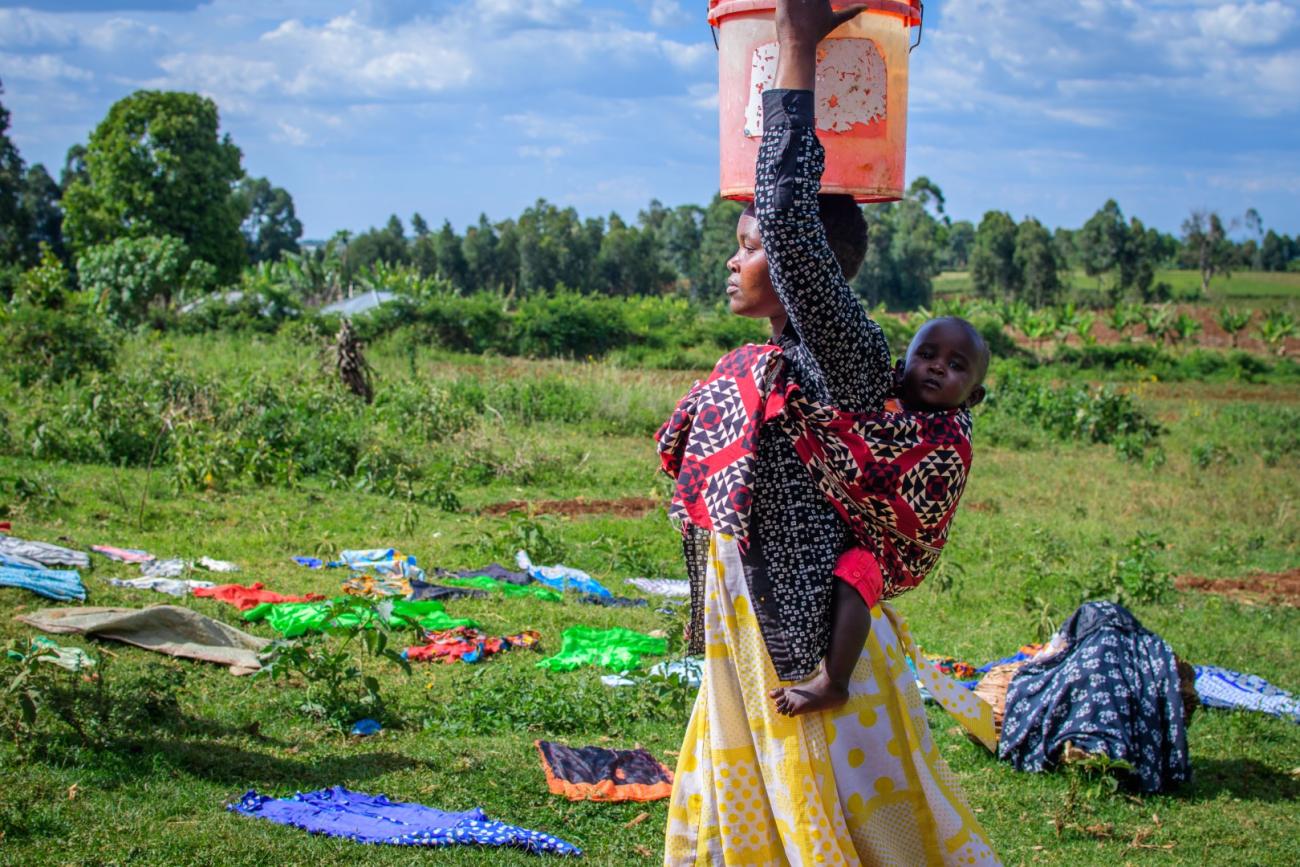 Woman carrying water and a baby